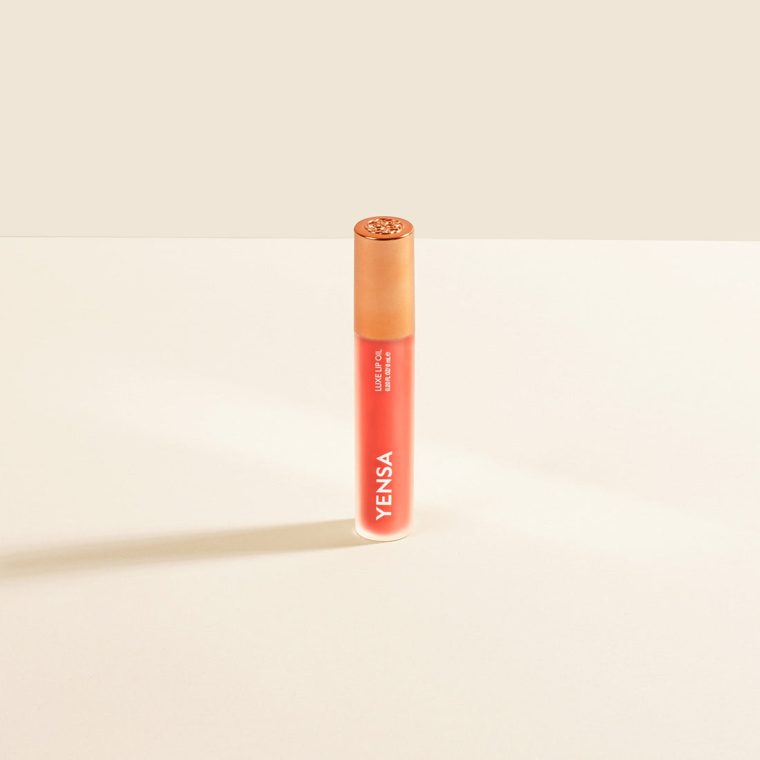 YENSA Luxe Lip Nourishing Oil with hyaluronic and vitamin E, featuring a vibrant coral lip gloss in a sleek tube.