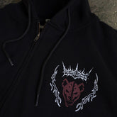 Black Mantra zip-up hoodie by Any Means Necessary Clothing with a front zipper and logo detail, close-up view.