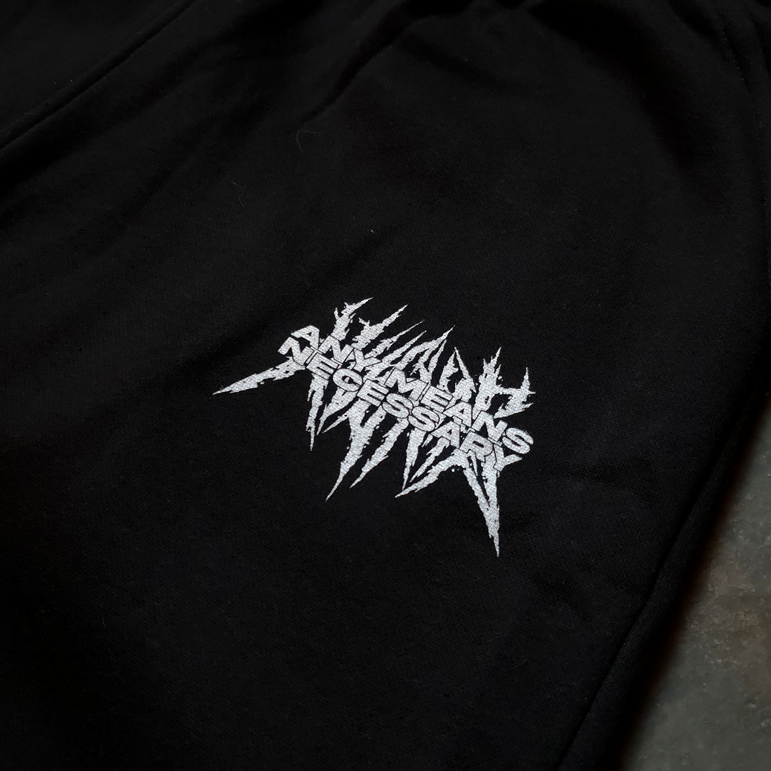 Close-up of black Mantra Sweatpants by Any Means Necessary Clothing, showing the fabric texture and waistband detail.