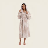 Unisex Ultraplush Australian Cotton Bathrobe by Italic, soft white plush fabric with a shawl collar and belt, hanging on a wooden hook.