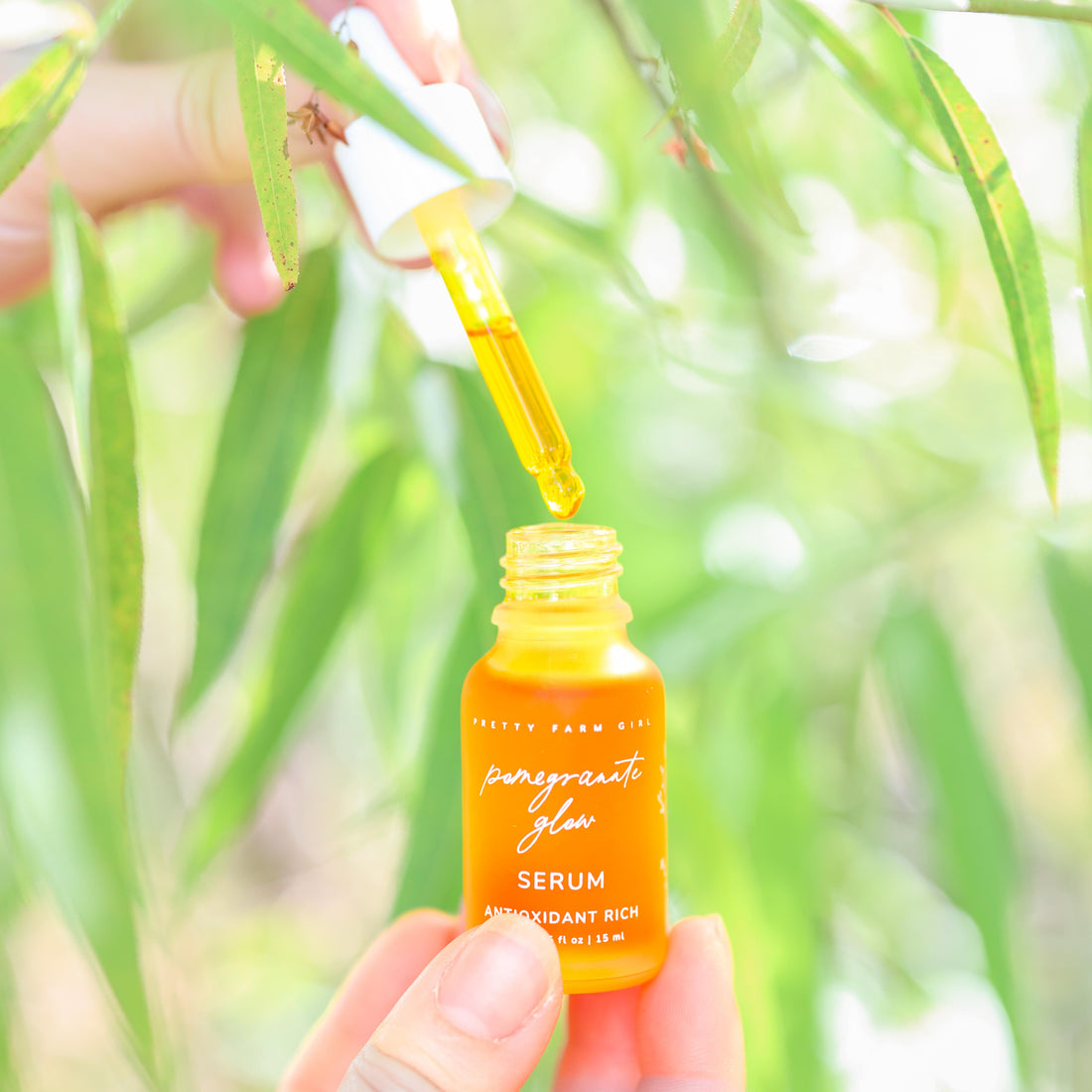 Pomegranate Glow natural face serum by Pretty Farm Girl, showing the 0.5 oz bottle with a pomegranate-themed label.