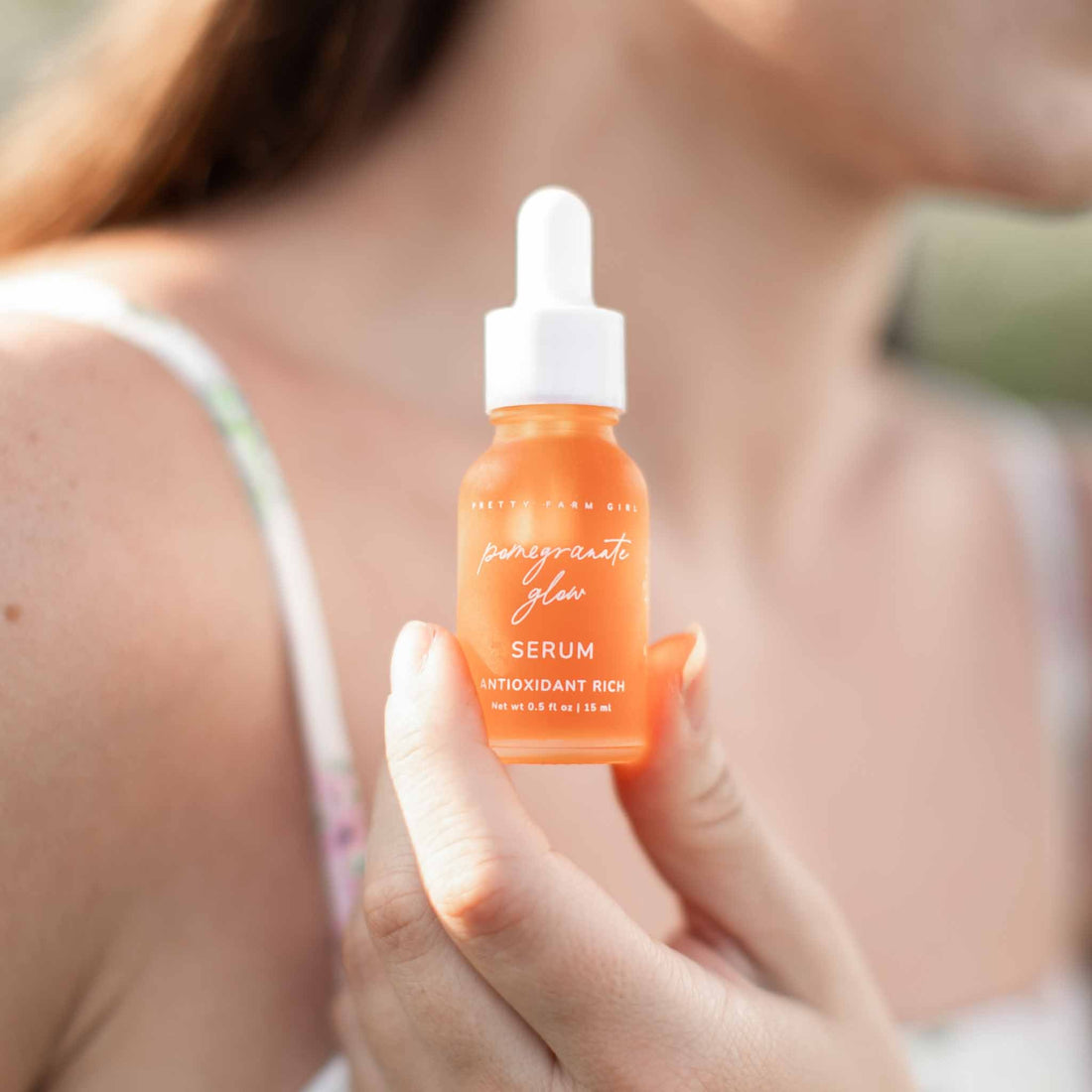 Pomegranate Glow face serum by Pretty Farm Girl in a clear dropper bottle, highlighting natural skin protection ingredients.