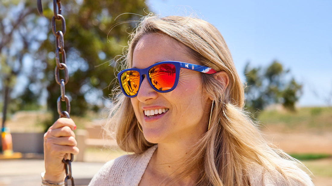 Female wearing U.S. Soccer 2024 Knockaround sunglasses, lifestyle shot highlighting sporty design and stylish look by Goal Five.