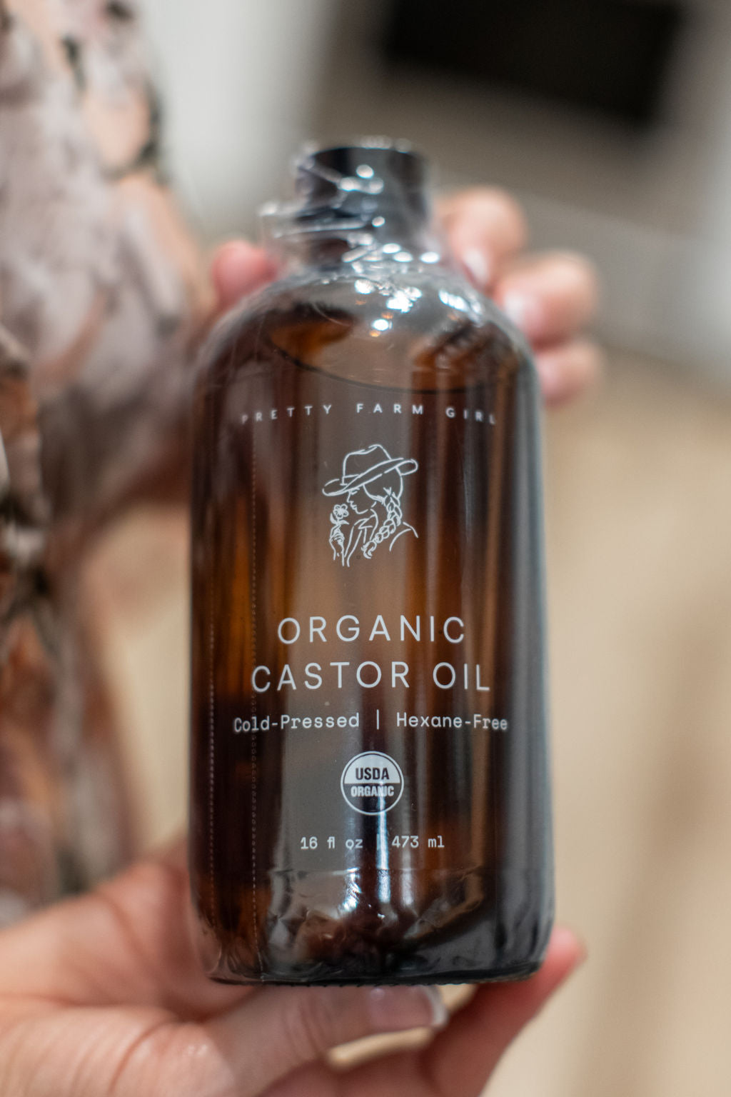 Bottle of Pretty Farm Girl pure organic cold-pressed hexane-free castor oil with a white label and pump dispenser.