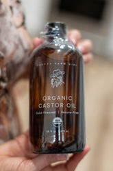 Bottle of Pretty Farm Girl pure organic cold-pressed hexane-free castor oil with a white label and pump dispenser.