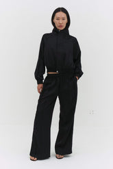 Black Leiseu track pants by findmenowthelabel, featuring a relaxed fit with an elastic waistband and side pockets.