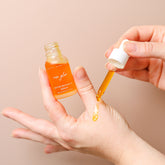 Pretty Farm Girl Rose Glow Anti-Aging Face Serum displayed on hand, highlighting a clear glass bottle with a rose-colored serum.