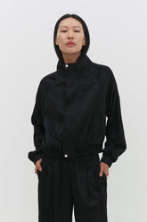 Black Leiseu track jacket by findmenowthelabel with a sleek design and zip-up front, displayed on a plain background.