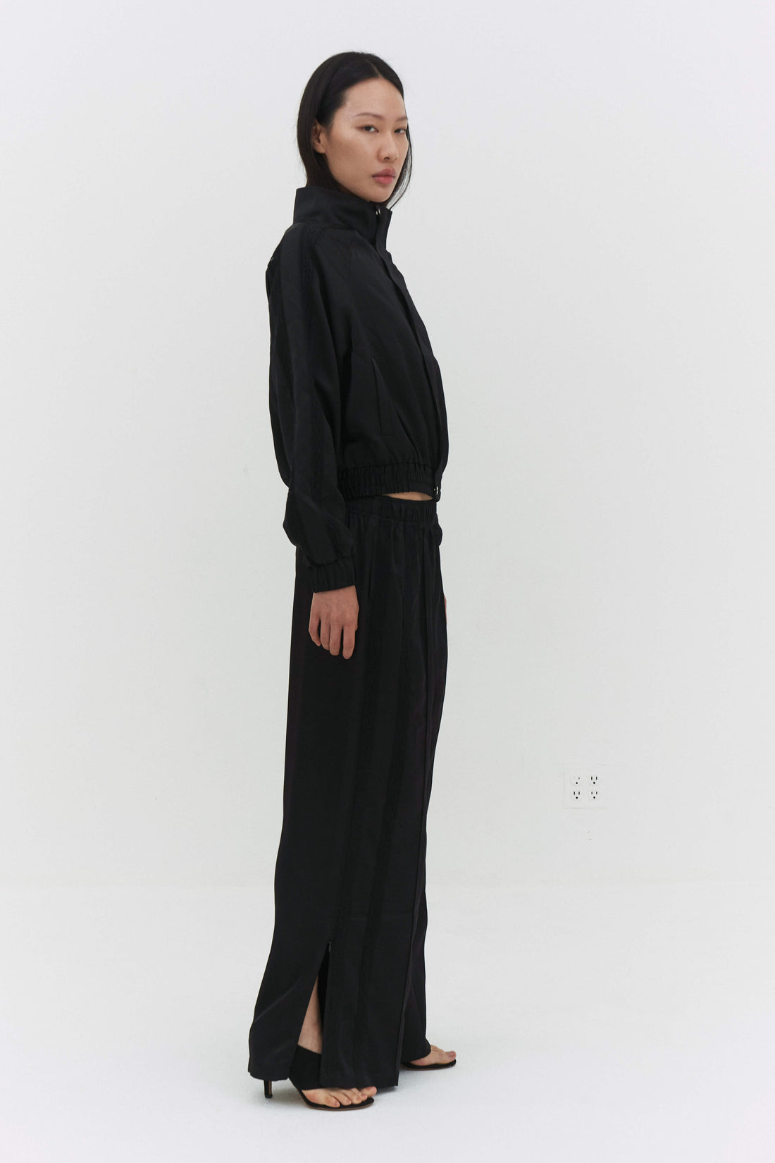 Black Leiseu track jacket by findmenowthelabel, featuring a sleek design and zip-up front on a plain background.