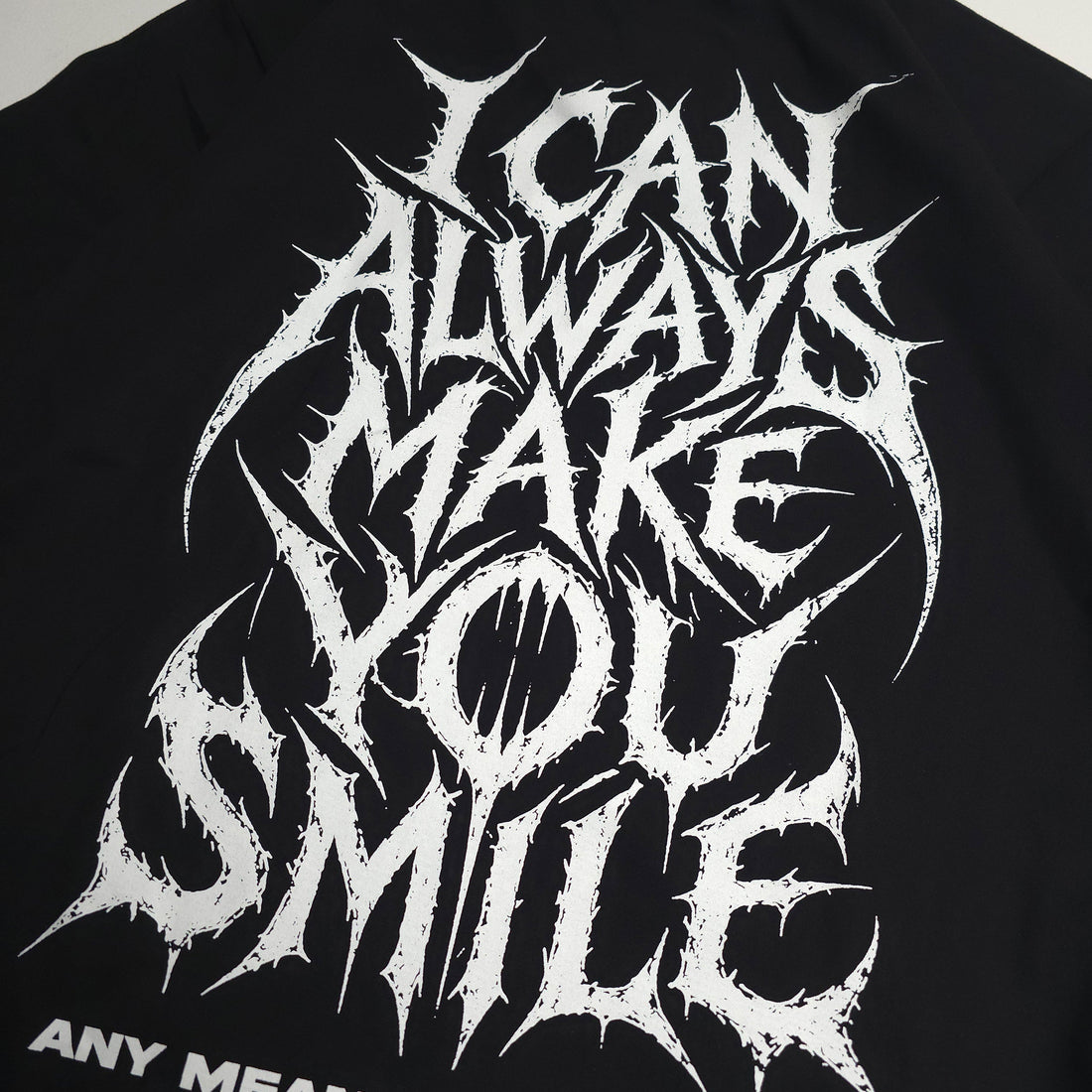Black Always Smile T-shirt from Any Means Necessary Clothing featuring a close-up of the smile graphic on the front.