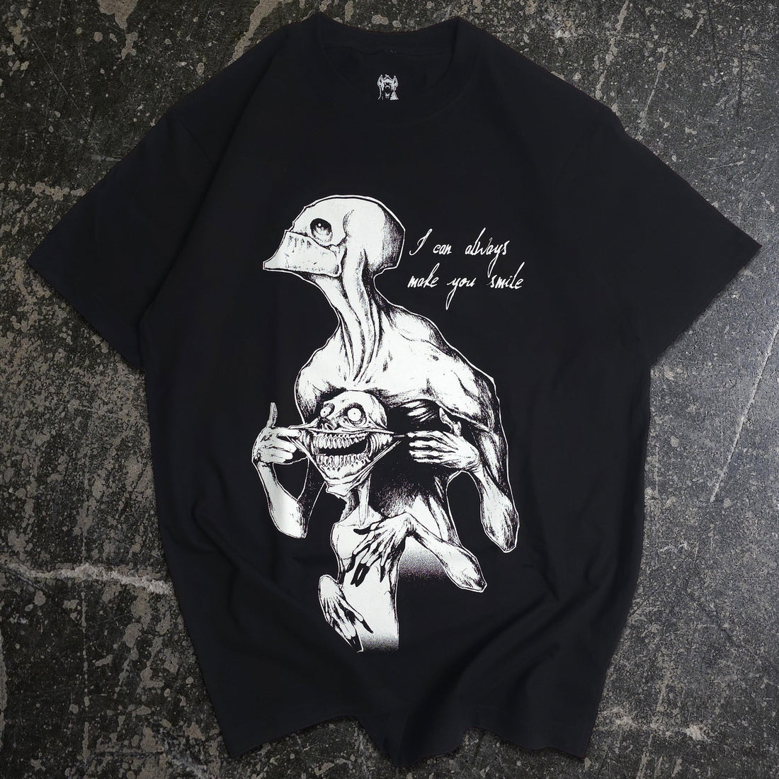 Black Always Smile T-shirt by Any Means Necessary Clothing featuring a front graphic of a smiling face on soft cotton fabric.