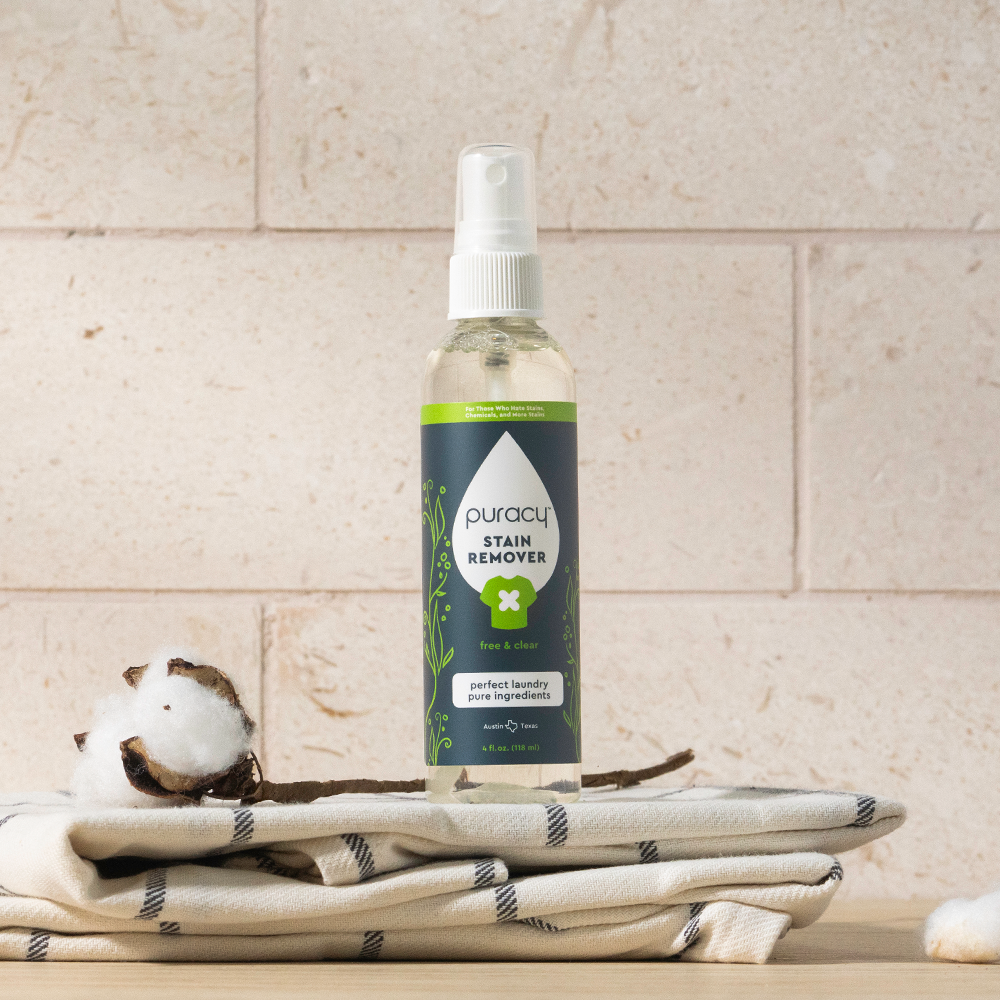 Puracy laundry stain remover bottle with a white label and orange cap, designed to target tough stains on clothing.