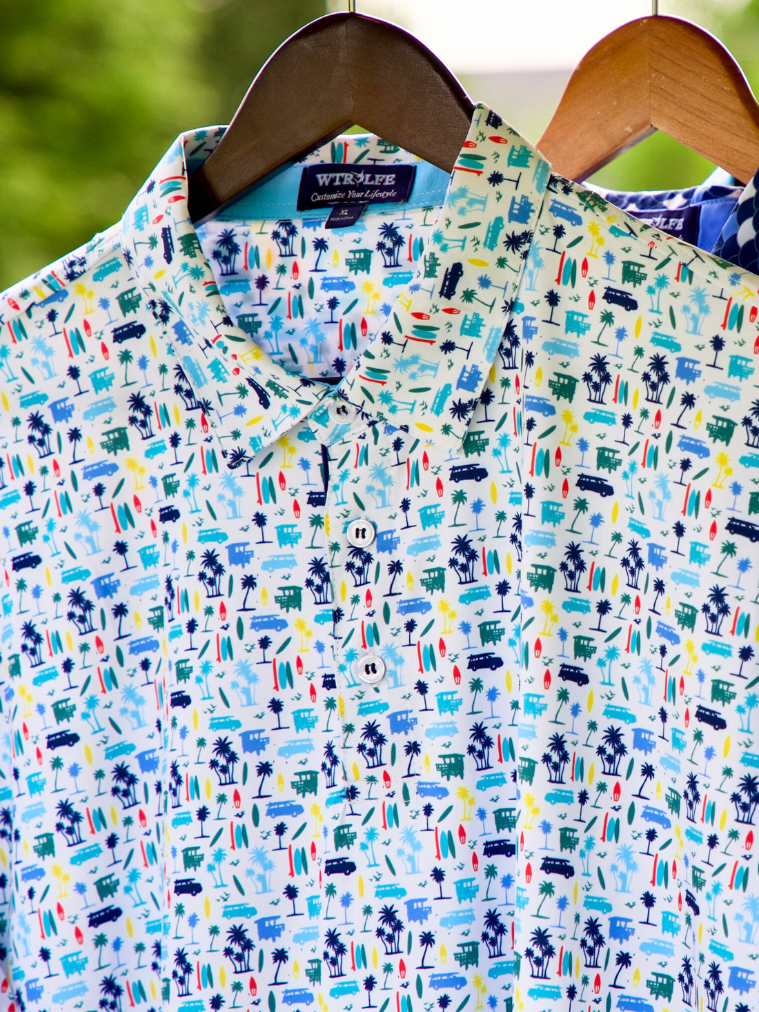 White Water Life Surfs Up Performance Polo hanging on a surfboard-shaped hanger, showcasing a stylish, breathable polo shirt for active wear.