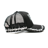 Black Thorns Trucker Hat by Any Means Necessary Clothing, side view showing mesh back and front with thorn design.