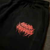Black "When Death Comes" sweatpants by Any Means Necessary Clothing with a close-up view of the design and fabric texture.