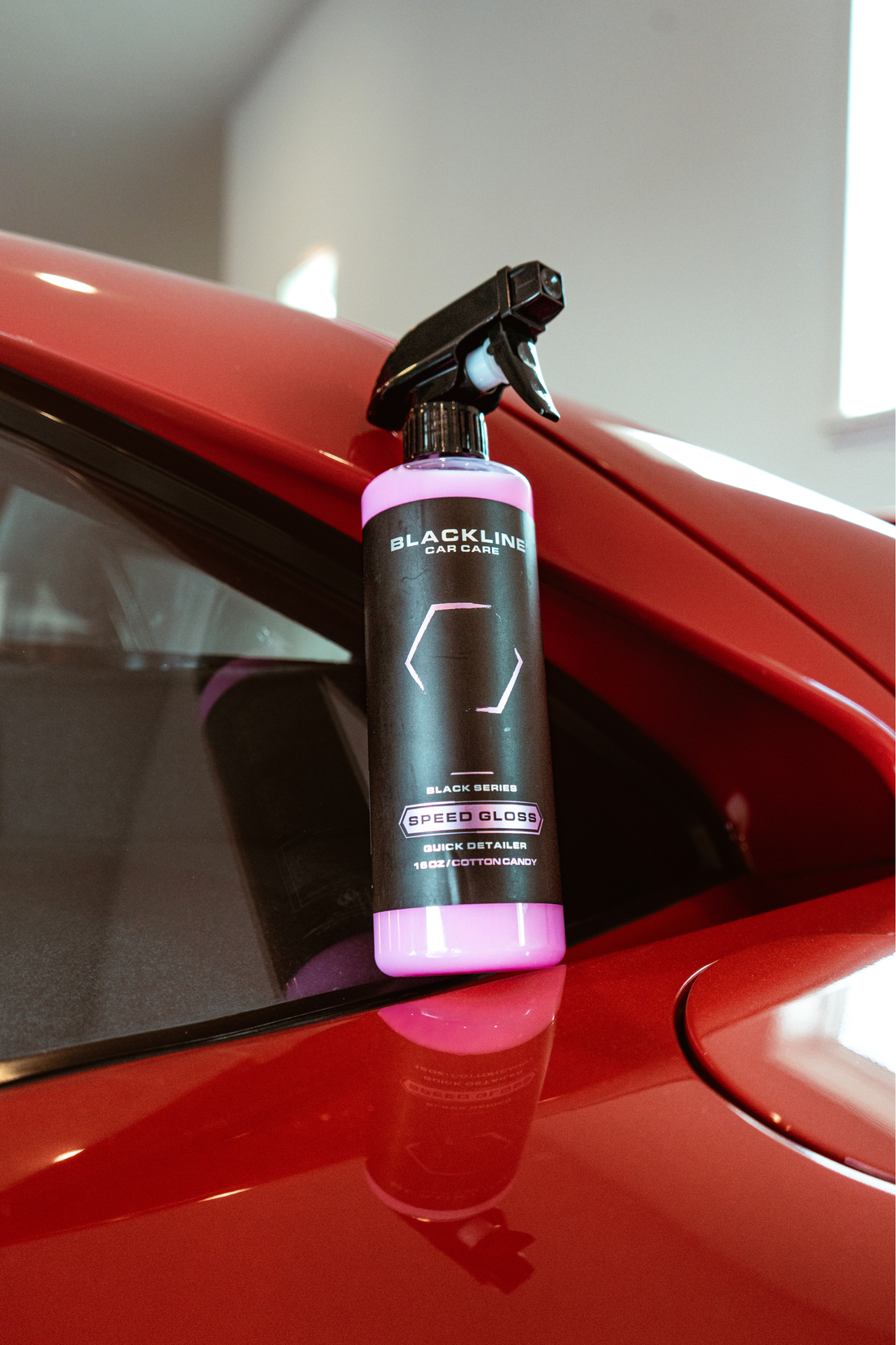 Blackline Car Care BLACKLINE® SPEED GLOSS Quick Detailer showing a sleek, glossy car surface with a spray bottle in the background.