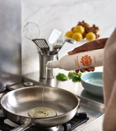 Bottle of Algae Cooking Oil from Algae Cooking Club, showing the label and clear plastic container with golden-colored oil.