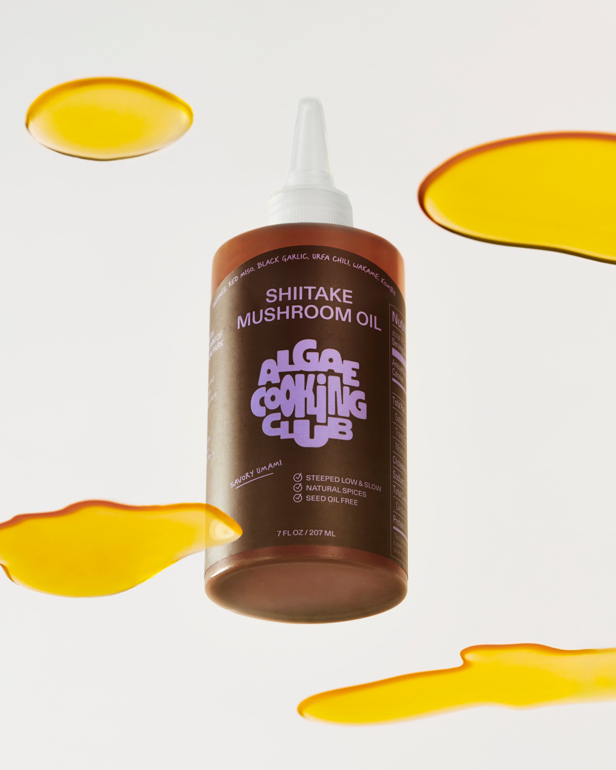 Bottle of mushroom-infused oil from Algae Cooking Club, showcasing clear glass container with dark mushroom-flavored oil.