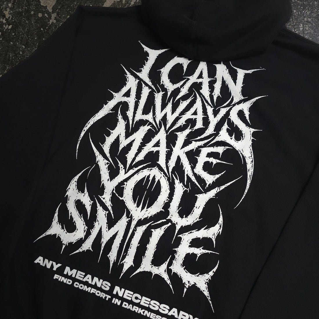 Black Always Smile Pullover Hoodie from Any Means Necessary Clothing, featuring a close-up of the smile graphic on the front.
