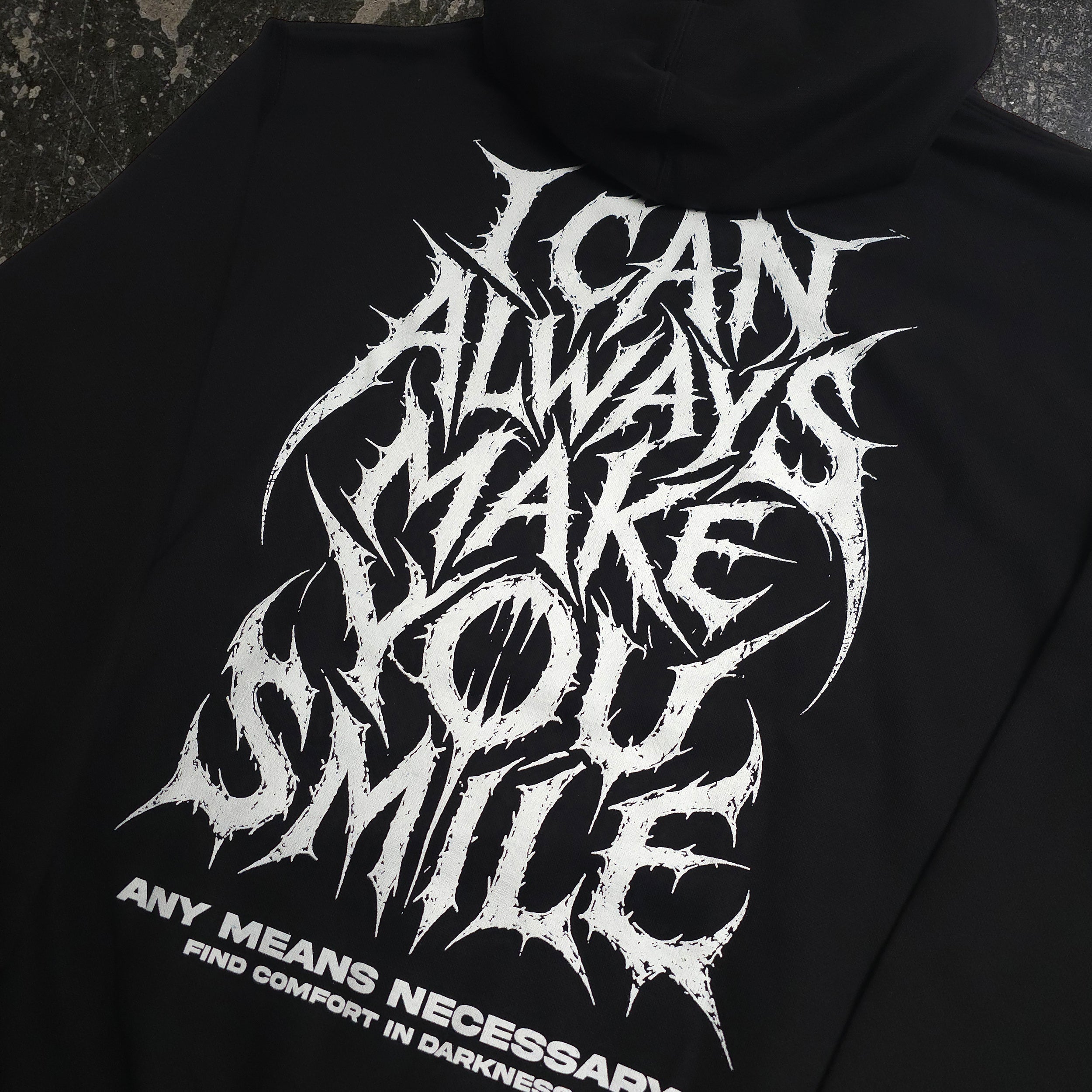 Black Always Smile Pullover Hoodie from Any Means Necessary Clothing, featuring a close-up of the smile graphic on the front.