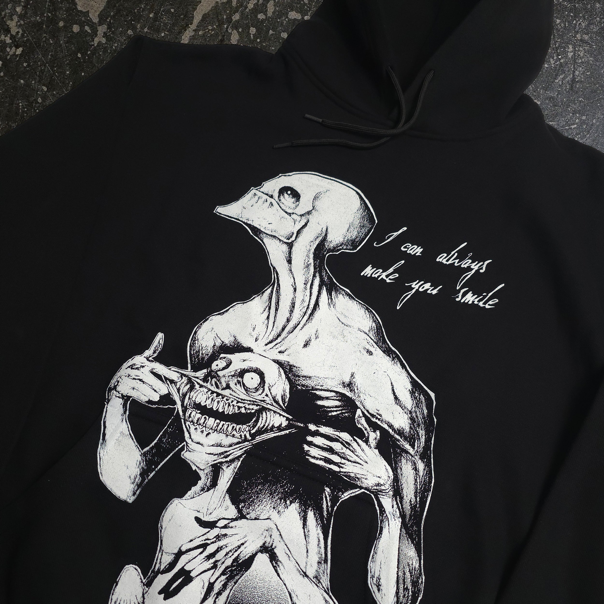 Black Always Smile Pullover Hoodie by Any Means Necessary Clothing, featuring a close-up of the smiling graphic on the front.