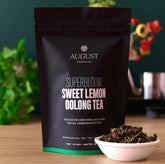 Box of August Uncommon Tea Superbloom Sweet Lemon Oolong Green Tea with 15 tea bags, showcasing fresh lemon slices and green tea leaves.