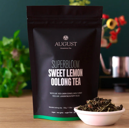 Box of August Uncommon Tea Superbloom Sweet Lemon Oolong Green Tea with 15 tea bags, showcasing fresh lemon slices and green tea leaves.