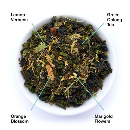 Cup of August Uncommon Tea Superbloom Sweet Lemon Oolong Green Tea in a tea bag, showcasing vibrant lemon flavor and green tea leaves.