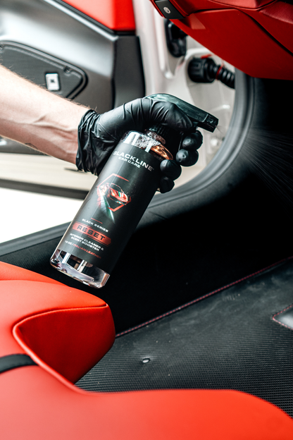 Blackline Car Care BLACKLINE RESET interior cleaner and scent booster spray on Italian leather surface, demonstrating cleaning action.