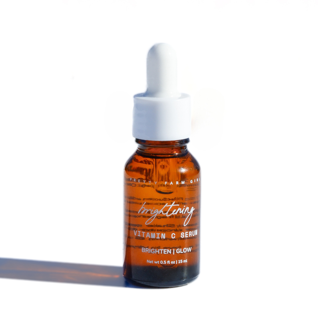 Pretty Farm Girl brightening face serum with vitamin C, featuring a clear glass bottle and dropper for skincare.