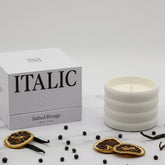 Salted soy wax ceramic candle by Italic, with a smooth white ceramic holder and a lit wick glowing softly.