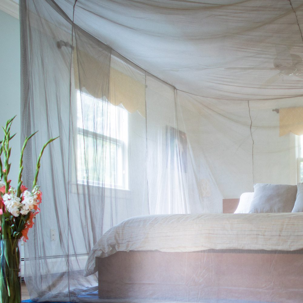 Shield Your Body SYB Faraday Bed Canopy outdoors with flowers, providing protection and privacy in a natural garden setting.