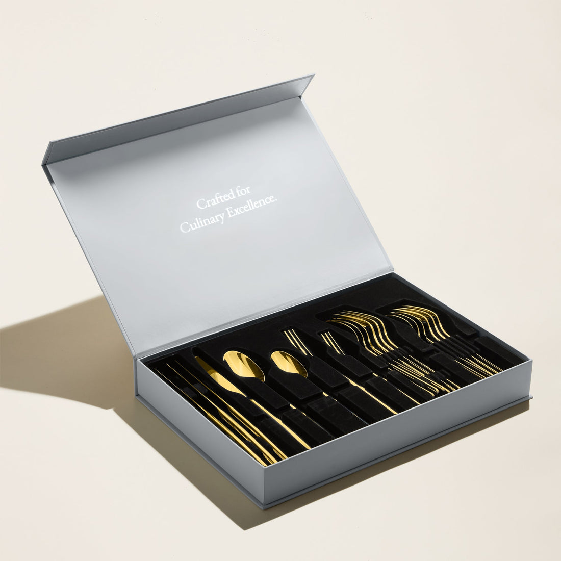 Golden Emilia Mirror 20-piece flatware set by Italic, featuring sleek handles and polished stainless steel utensils.