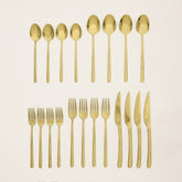 Italic Emilia gold 20-piece flatware set with sleek forks, knives, spoons, and serving pieces on a white background.