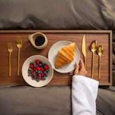 Italic Emilia Mirror 20-Piece Gold Flatware Set with sleek, reflective stainless steel utensils on a white background.