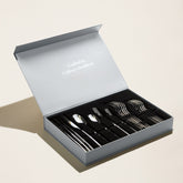 Italic Emilia 20-piece silver flatware set featuring polished forks, knives, spoons, and teaspoons arranged on a white background.