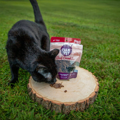 Farm To Pet beef crumbles cat treats in a bag, showing a cat sniffing the front of the package, high-protein snack for cats.