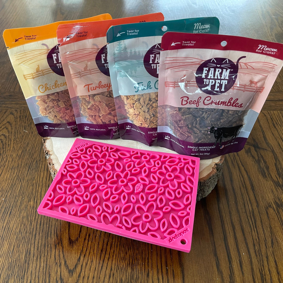 Farm To Pet chicken crumble cat treats on pink flower lick mat, single-ingredient treats for cats with chicken flavor.