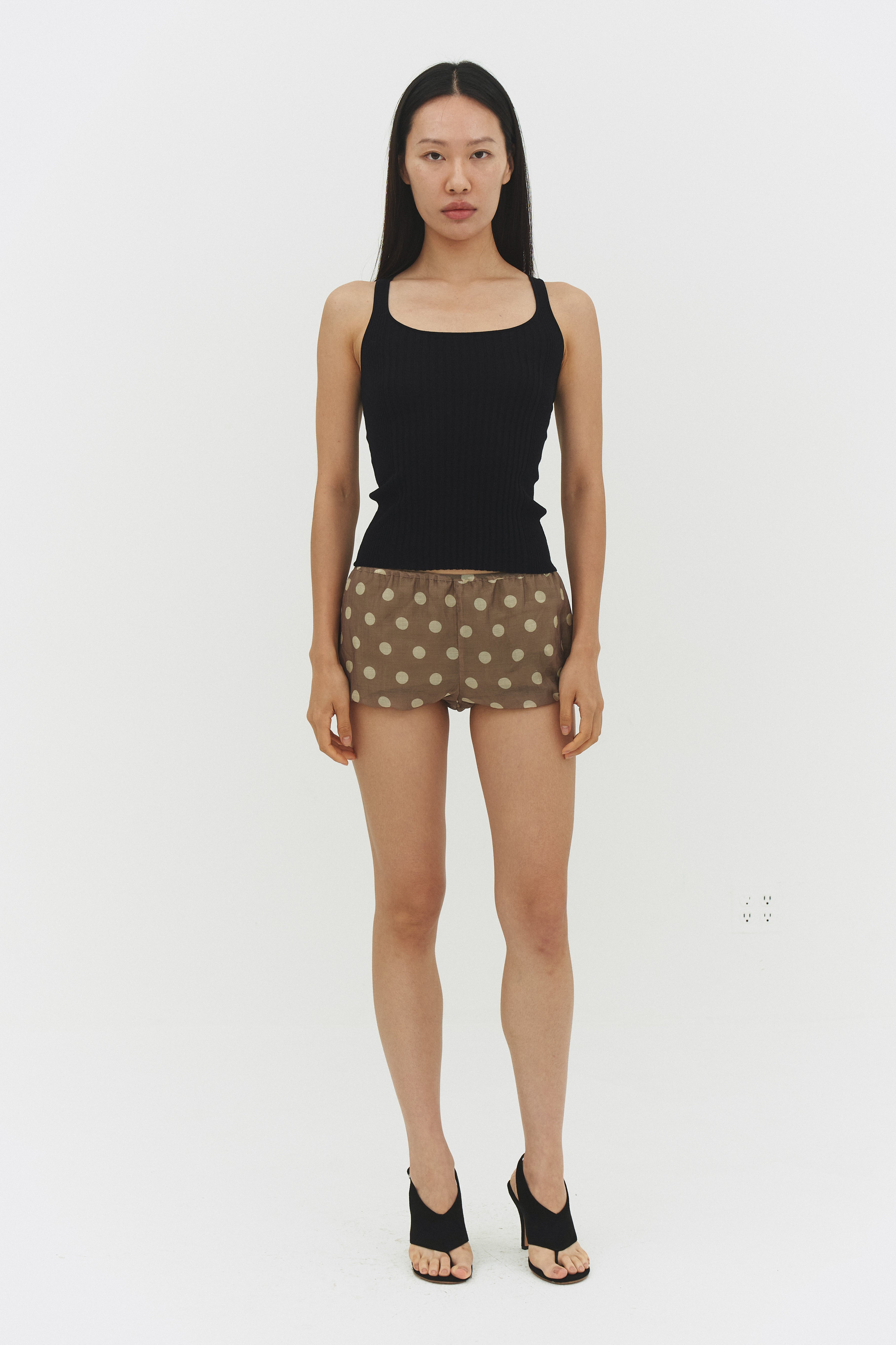 Black ribbed knit tank top from findmenowthelabel, close-up of sleeveless knitwear with textured ribbing.