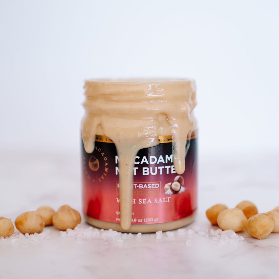 Jar of House of Macadamias macadamia nut butter with sea salt flavor on a white background, showing the product label and creamy texture