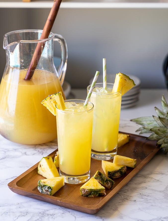 Igotchu Pineapple Lemonade juice in a clear glass with fresh pineapple and lemon slices on the side.