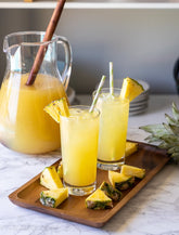 Igotchu Pineapple Lemonade juice in a clear glass with fresh pineapple and lemon slices on the side.