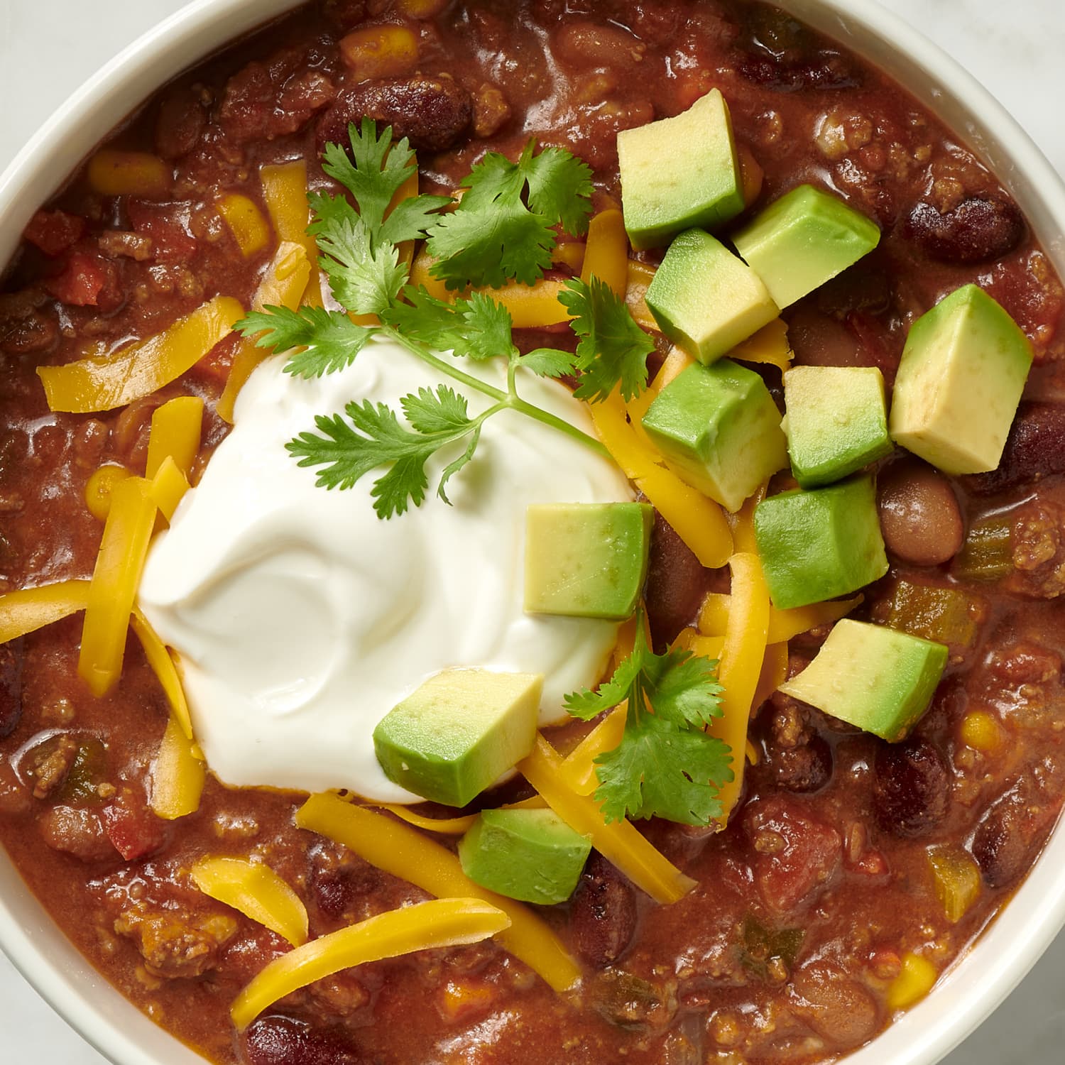 Igotchu Chili Seasoning container with a bowl of spicy chili dish garnished with fresh herbs and chili peppers.