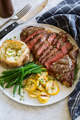 Igotchu Steak Seasoning jar with seasoning blend for enhancing grilled and cooked steaks, shown on a rustic wooden surface.