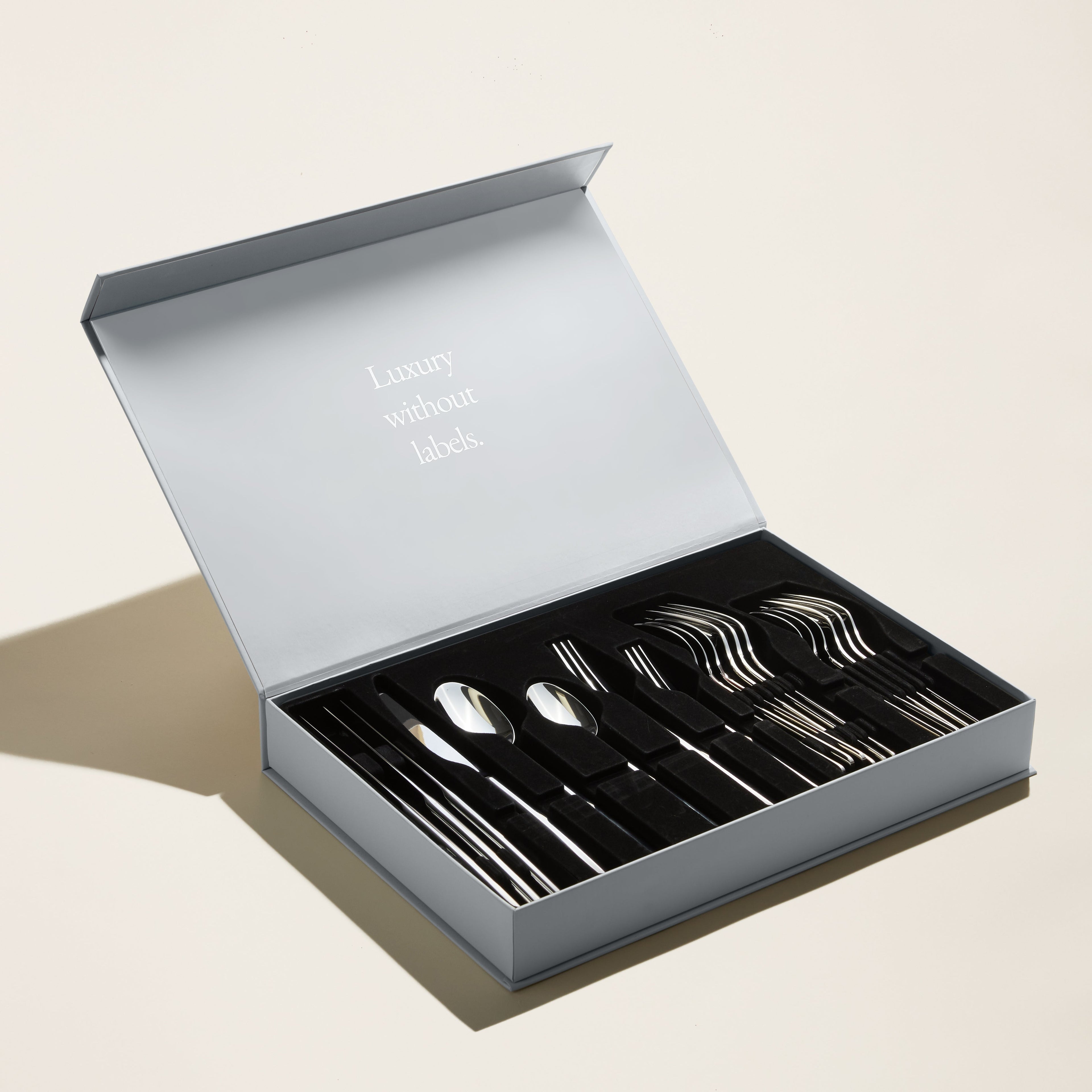 Italic Emilia Mirror 20-piece flatware set with polished stainless steel forks, knives, spoons, and teaspoons displayed on a white background.