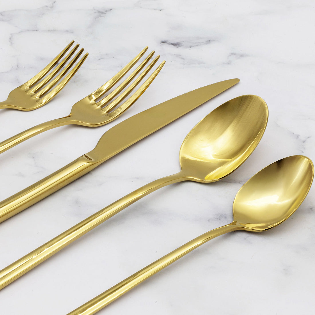 Italic Emilia gold 20-piece flatware set featuring sleek forks, knives, spoons, and a polished finish on a reflective surface.