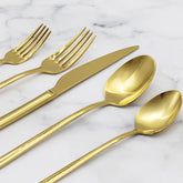 Italic Emilia gold 20-piece flatware set featuring sleek forks, knives, spoons, and a polished finish on a reflective surface.