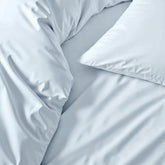 Soft white Luxe Australian Sateen Sheet Set from Italic on a neatly made bed with smooth, shiny satin fabric for a luxurious sleep.