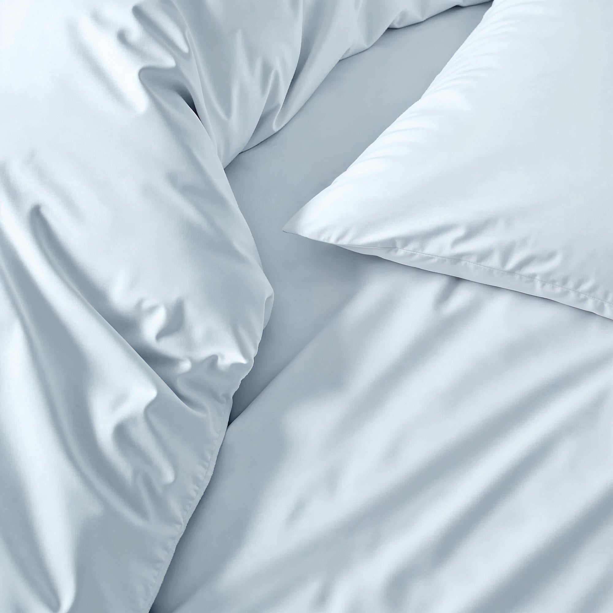 Soft white Luxe Australian Sateen Sheet Set from Italic on a neatly made bed with smooth, shiny satin fabric for a luxurious sleep.