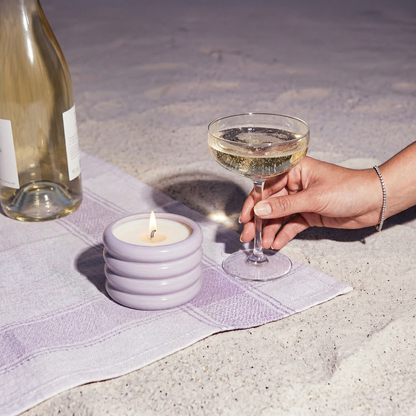 Italic soy wax ceramic candle in lilac color with a smooth ceramic container, set outdoors with natural light.